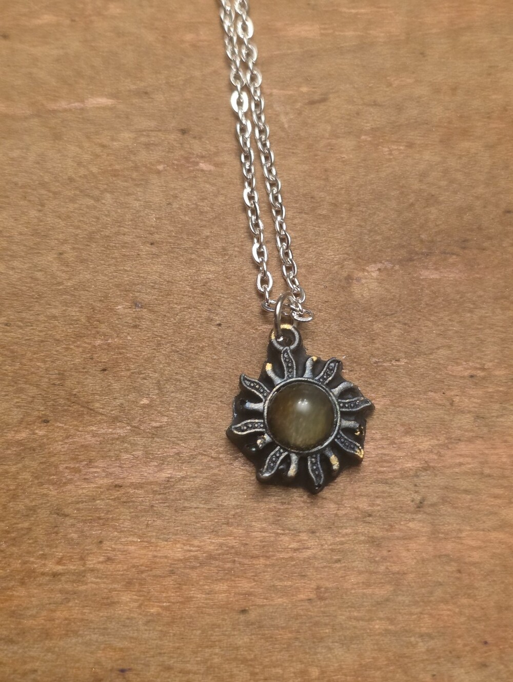 Black And Gold Resin Pendant With Central Gold Gemstone On A Silver Tone Chain